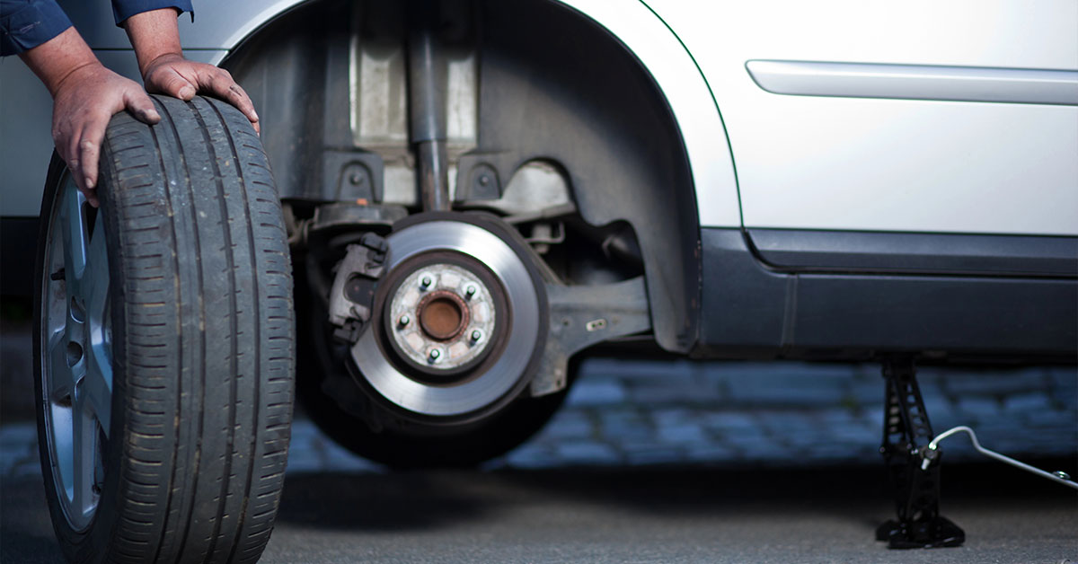 Mechanic holding car tyre as he has just removed it from the vehicle.