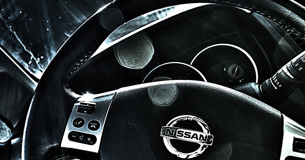 A close up photo of a steering wheel of a Nissan vehicle.