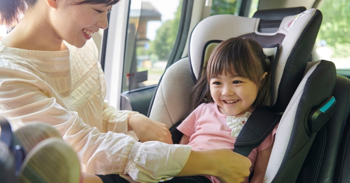 Mother Buckling Her Daughter into a Car Seat.